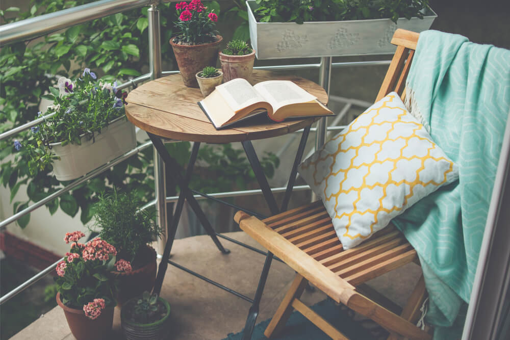 Balkon mit Stuhl, Tisch Buch und Blumen im Topf